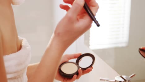 woman applying make-up on her face in bathroom