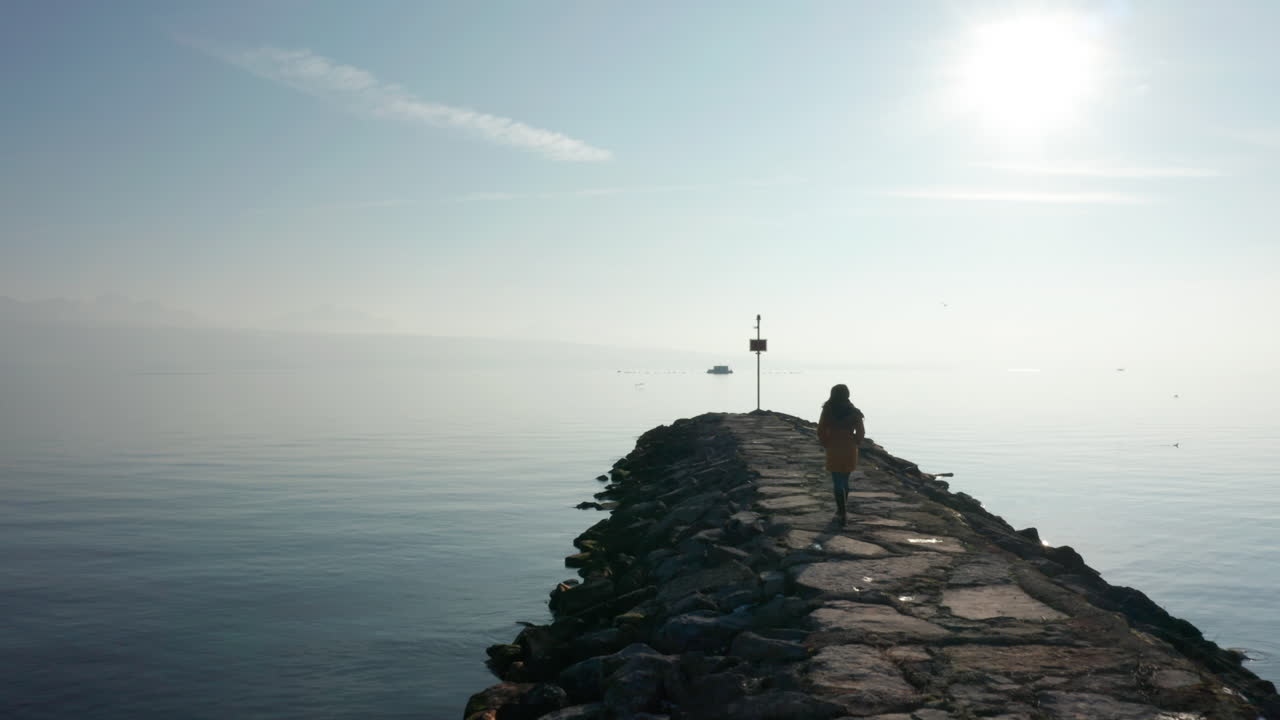 Woman walking over stone quay at the edge of a gorgeous lake