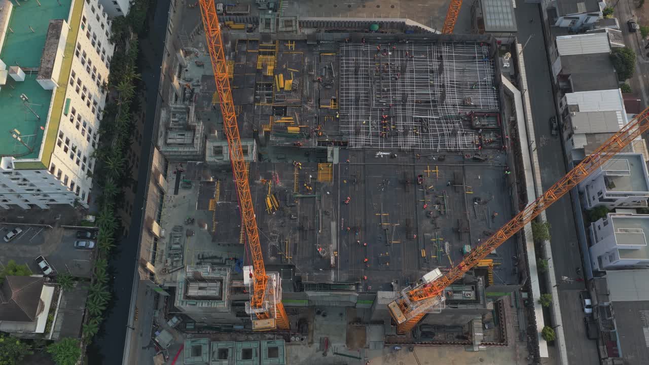 High aerial top down view of a large building under construction. Workers and engineers are busy working at the construction site