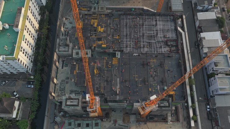 High aerial top down view of a large building under construction. Workers and engineers are busy working at the construction site