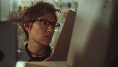 female detective taking file from shelf and examining evidence board