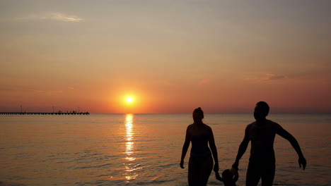 Familia-Joven-En-La-Playa-Bajo-Una-Colorida-Puesta-De-Sol