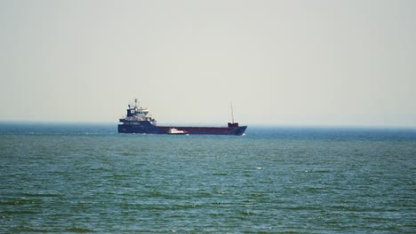 huge container ship after emptying cargo at nearby port with support vessel as it exits swansea bay in south wales. headed to destination to pick up goods for importing and exporting shipping.