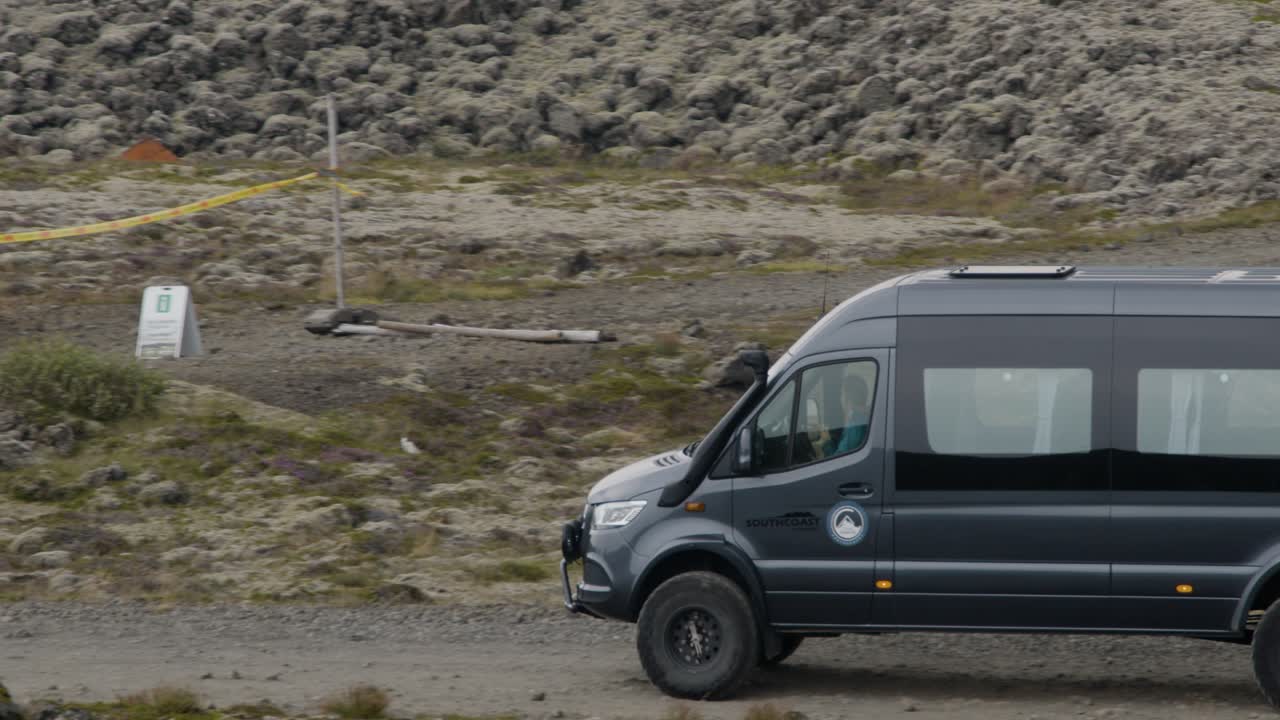 A tour bus arrives at a busy spot where people have gathered to see the erupting Grindavik volcano in Sundhnúkur crater, Iceland.