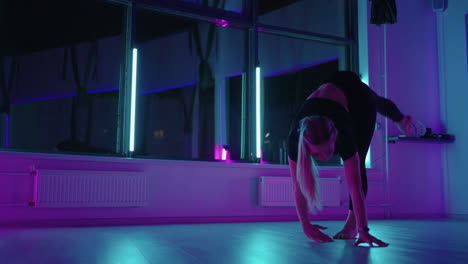 A-woman-dances-in-a-studio-with-a-neon-light-performing-graceful-exercises-and-movements-from-stretching-and-dancing-in-slow-motion