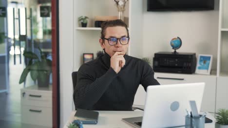 The-man-with-glasses-is-sitting-at-a-desk-in-the-office-and-making-a-Zoom-call-online