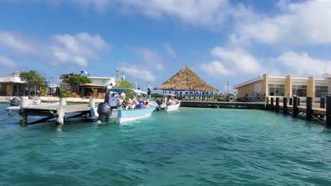 caribbean tourist pier with people inside motor boats ready to go beach, los roques