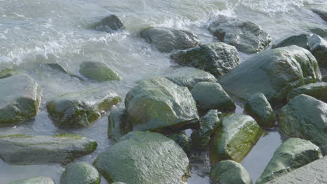 Ruhige-Wellen-über-Moosigen-Felsen.-Nahaufnahme