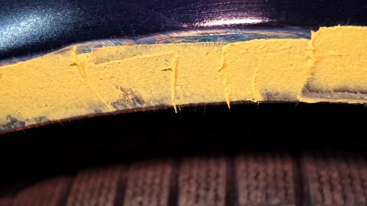 Applicazione di stucco per carrozzeria su un parafango di veicolo danneggiato durante il servizio di riparazione in primo piano.
