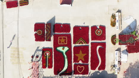 bright red flower arrangements arranged on a wall, forming star and circular patterns