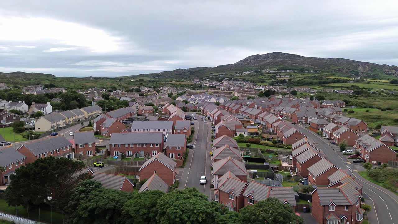 Aerial view modern red brick housing neighbourhood streets under Holyhead mountain in Wales