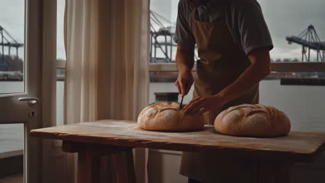 baker scoring artisan bread by a window