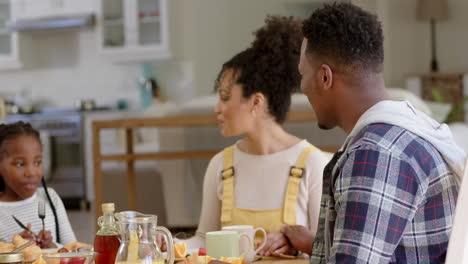 Happy-african-american-parents-and-daughter-having-breakfast-at-home,-slow-motion