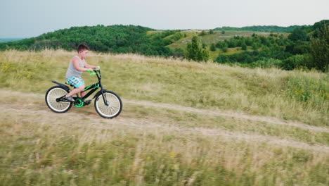 Ein-Kleiner-Lächelnder-Junge-Kommt-Auf-Einem-Fahrrad-Von-Einem-Hügel-Herunter-1