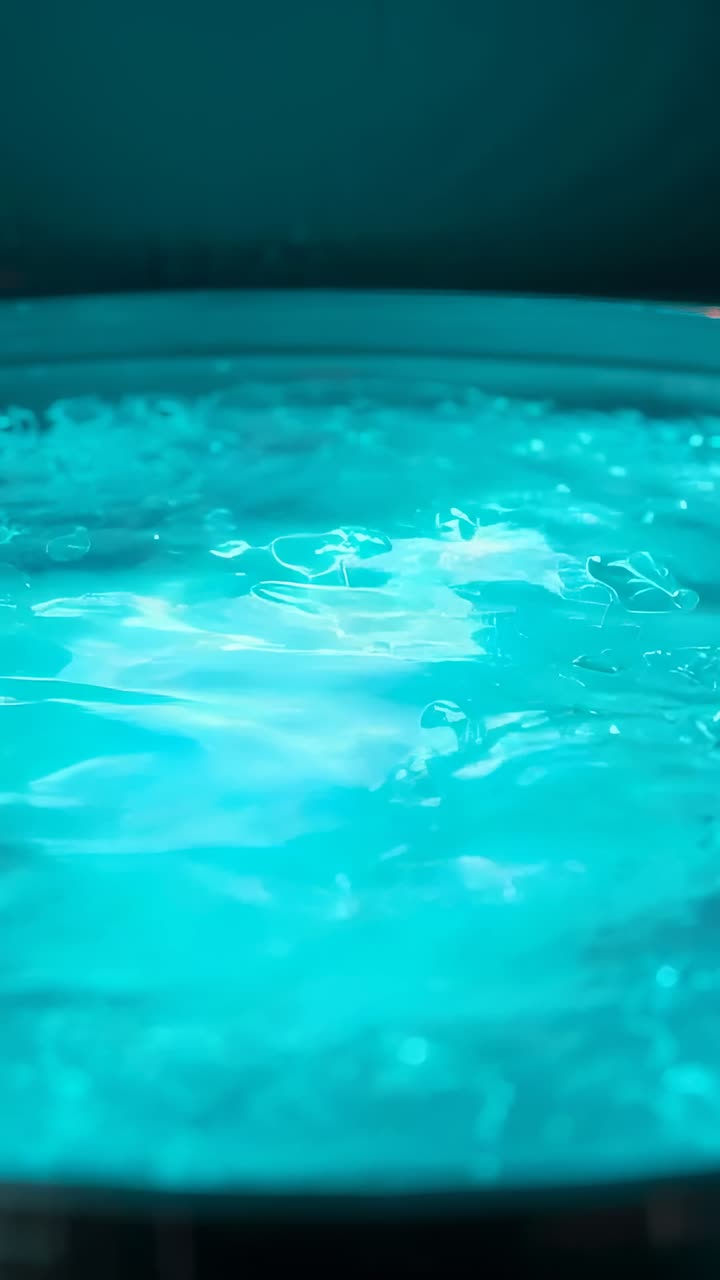 Video verticale: superficie dell'acqua color verde acqua increspata dai getti idromassaggio della spa, che mostra il bordo della vasca