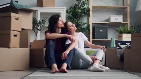 couple sitting in their new apartment surrounded by moving boxes