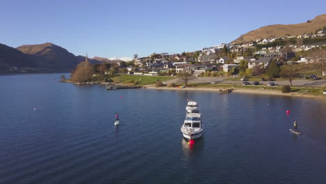 paddleboarder in paddling in a blue bay next to moored boats