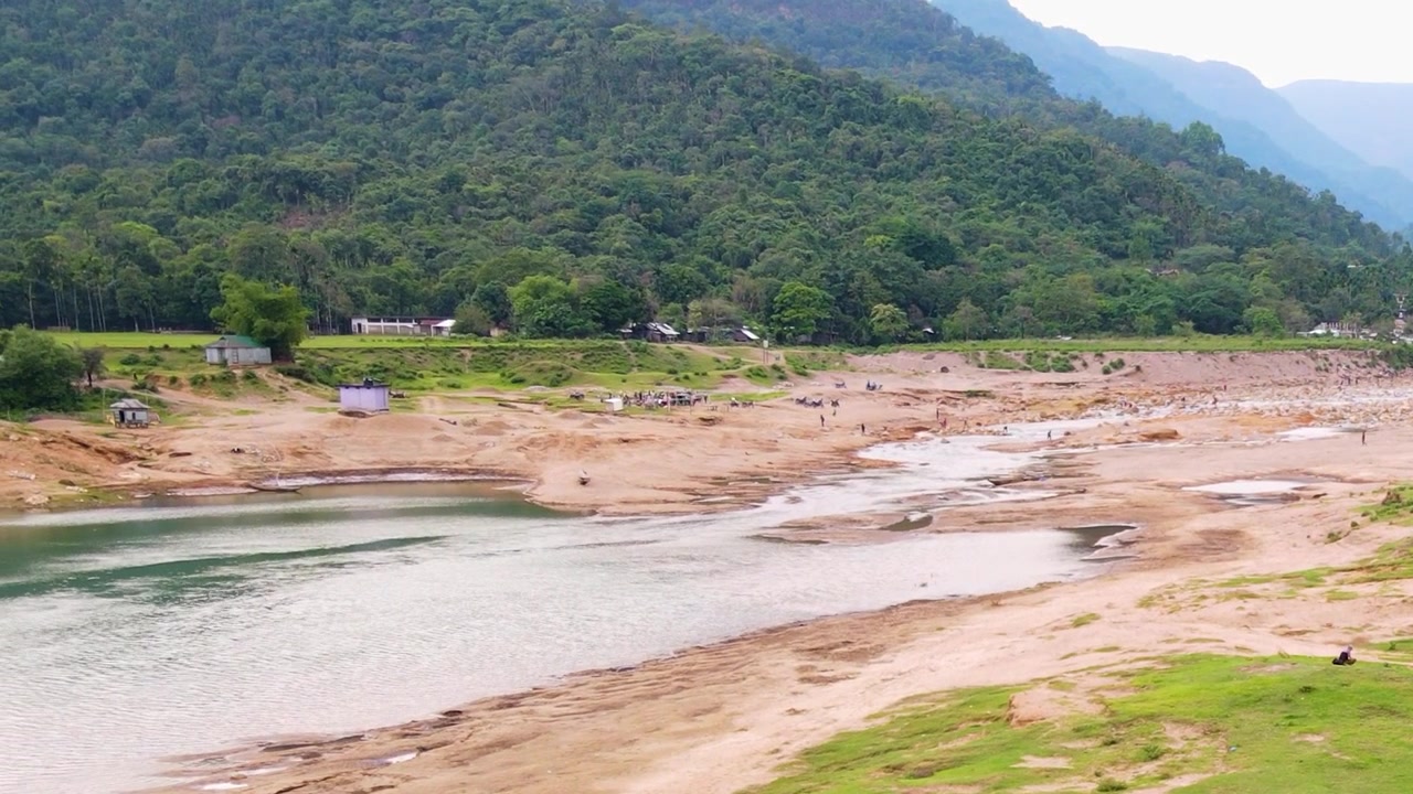 Veduta aerea con drone del fiume Piyain a Bichanakandi con le colline del Meghalaya al confine con l'India, conservazione ambientale, estrazione di sabbia e clima
