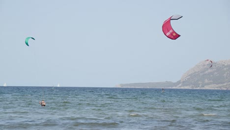 Drei-Personen-Kitesurfen-In-Glasklarem-Wasser-Auf-Den-Baleareninseln-Mallorcas,-Umgeben-Von-Bergen