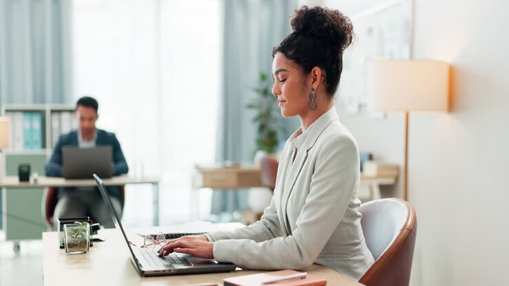 Woman with desk, laptop and typing in coworking