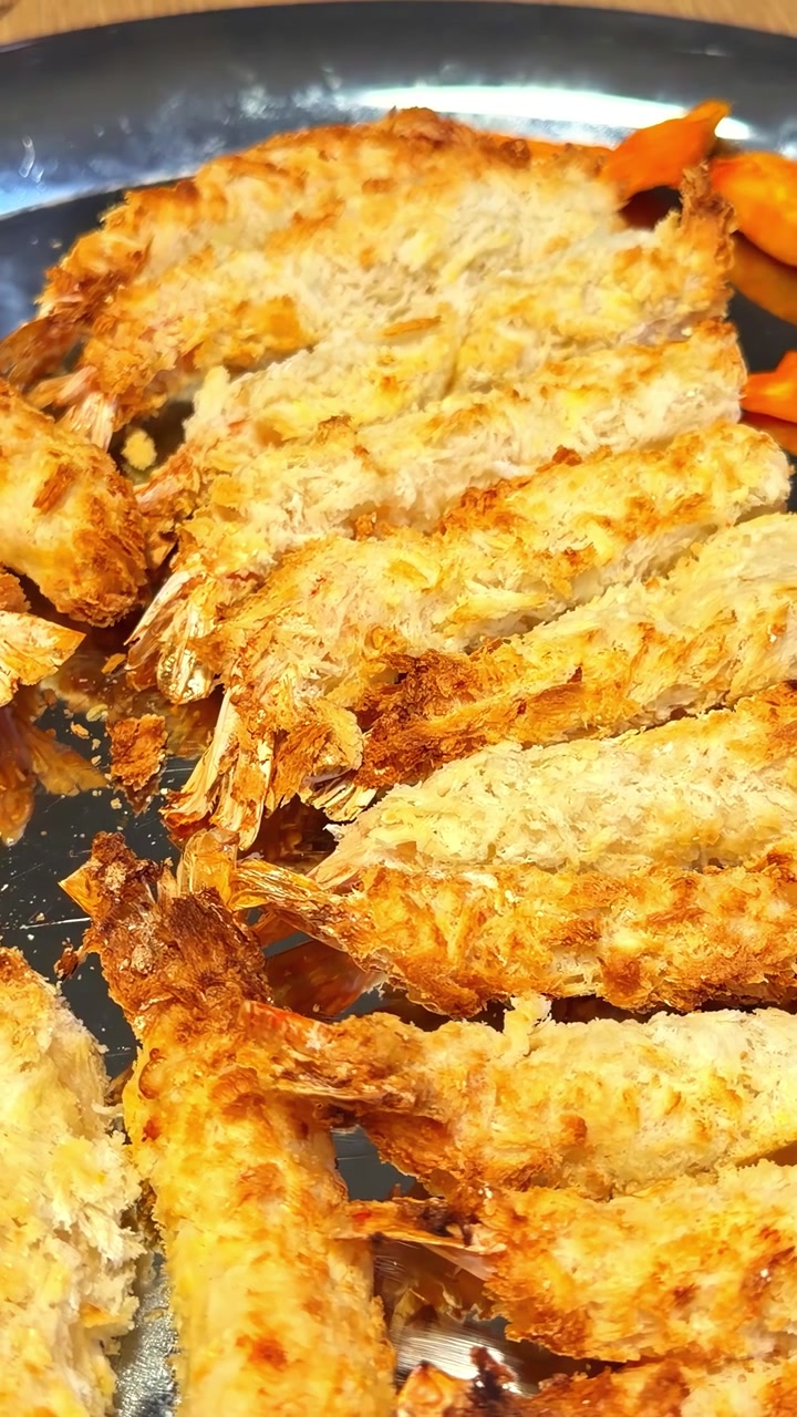 銀の皿に盛り付けられた黄金色の揚げエビのクローズアップ。そのサクサクとした食感が際立ち、料理のプレゼンテーションやメニューデザインに最適です。
