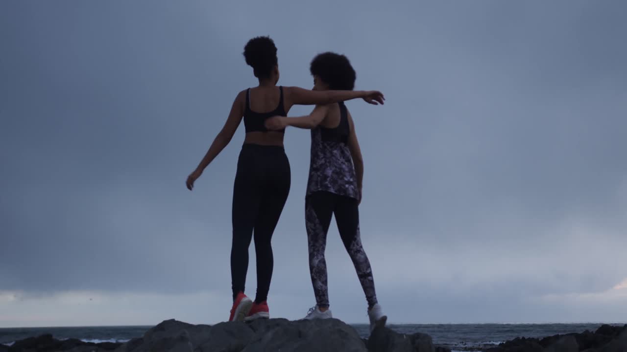 dos mujeres de raza mixta abrazándose en la playa