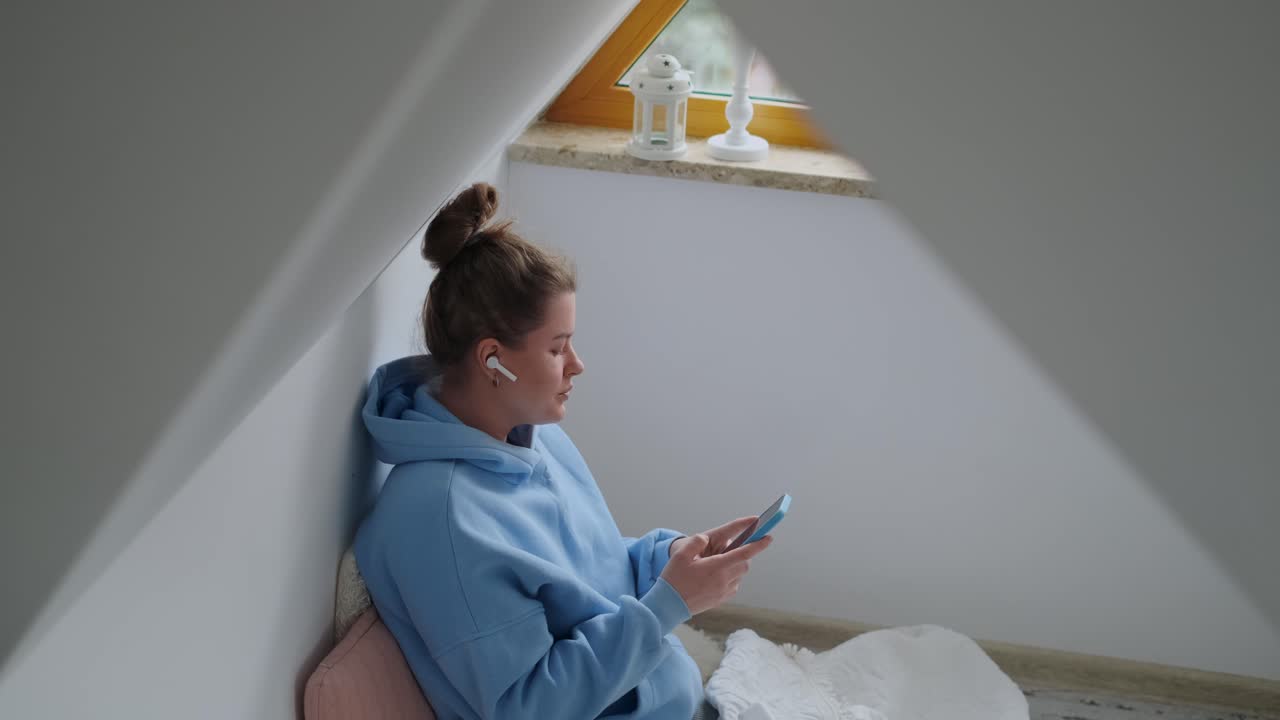 Donna che usa il telefono in un'accogliente camera da letto in mansarda