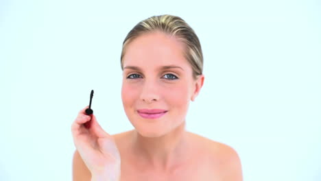 blond woman making up her eye with mascara