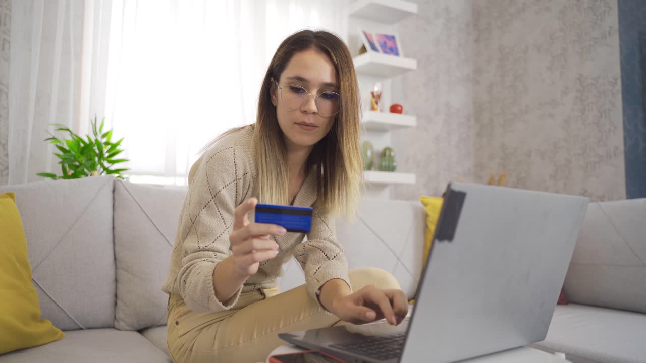 Giovane donna che fa acquisti a casa con una carta di credito