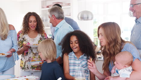 slow motion shot of multi-generation family and friends gathering in kitchen for celebration party