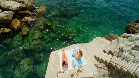 women sunbathing on a cliffside beach