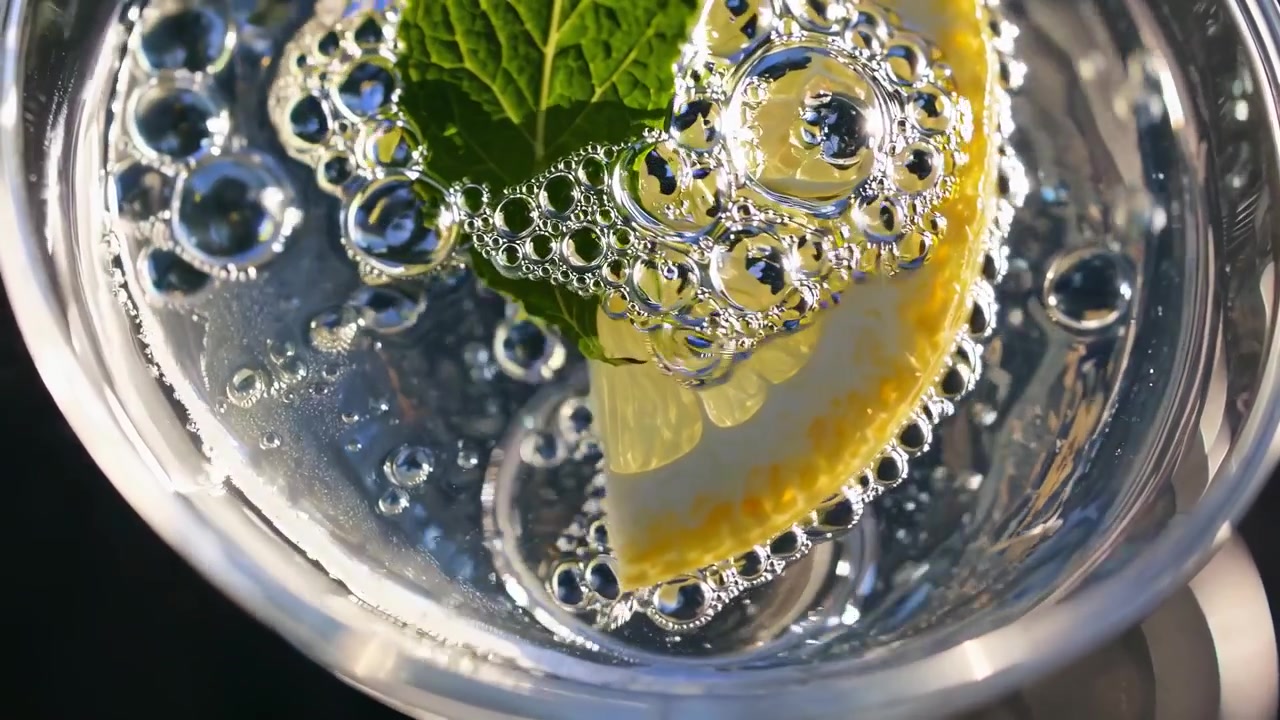 Acqua frizzante rinfrescante con fetta di limone e foglia di menta.