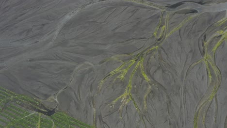 inclinación aérea del dron hacia abajo desde la montaña islandesa marrón hasta el campo verde cubierto de hierba