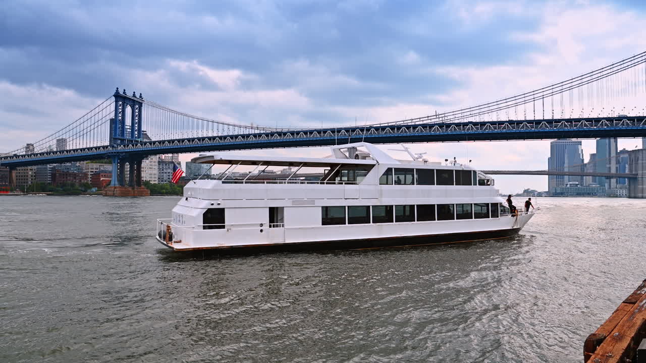 Moderne flodbåd med amerikansk flag bagpå sejler forbi East River. Fartøj på vej mod Manhattan Bridge. New York, USA