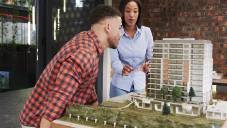 diverse male and female architect discussing architectural model, slow motion