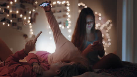 Adolescentes-Felices-Acostadas-En-La-Cama-Tomando-Fotos-Selfie-Usando-Un-Teléfono-Inteligente-Riéndose-Divirtiéndose-Durmiendo-El-Fin-De-Semana