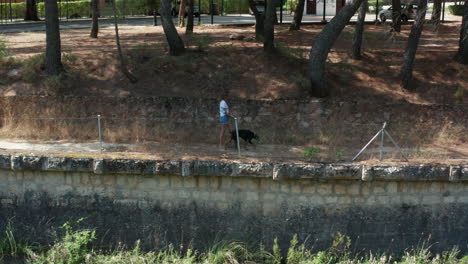 Foto-De-Seguimiento-De-Una-Joven-Paseando-A-Su-Perro-Mascota-Por-Los-Senderos-Del-Lago-De-Bolarque