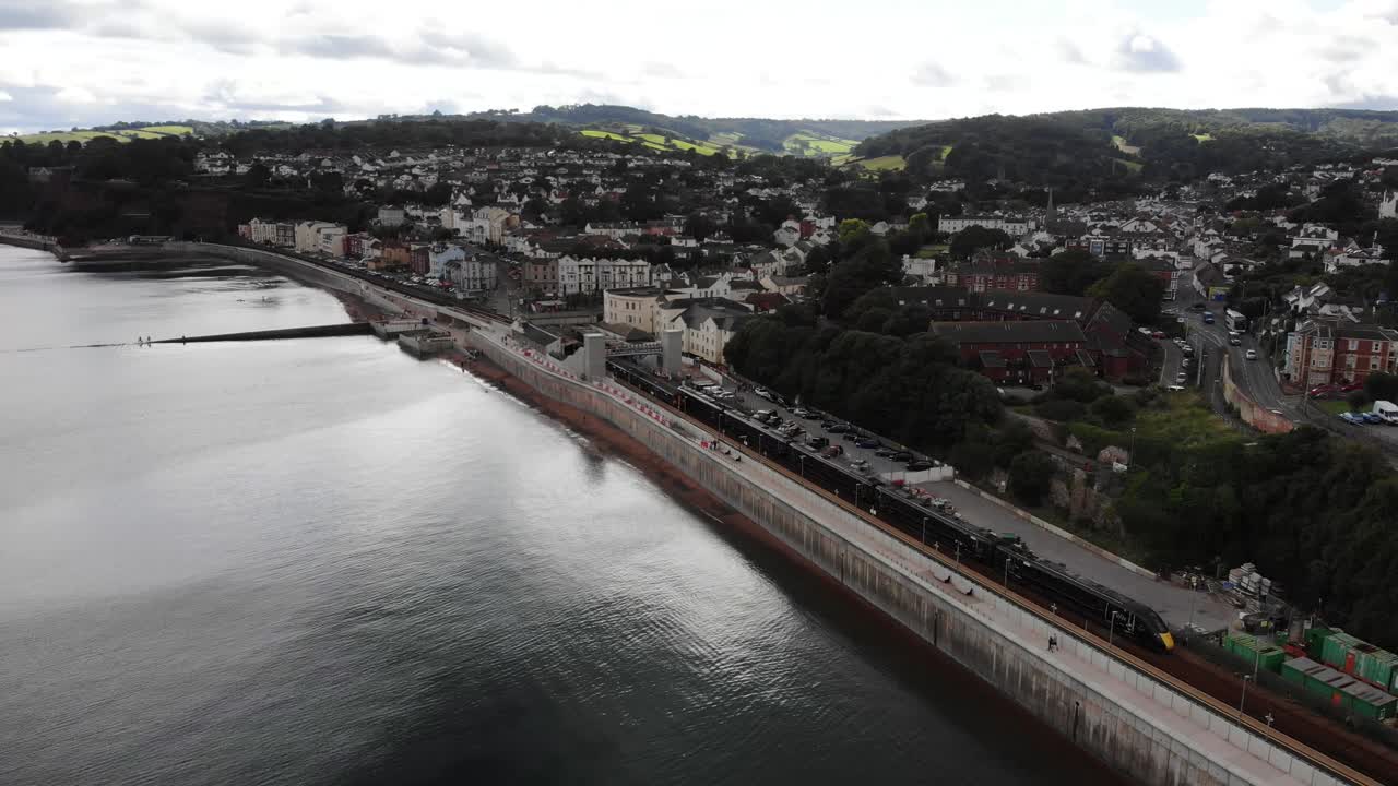Aerial view of a train passing next to the sea in the town of Dawlish, located in Devon, England, a popular seaside resort town