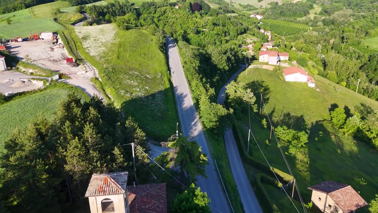 Volo di drone sopra una chiesa storica e rigogliose colline verdi nella campagna italiana