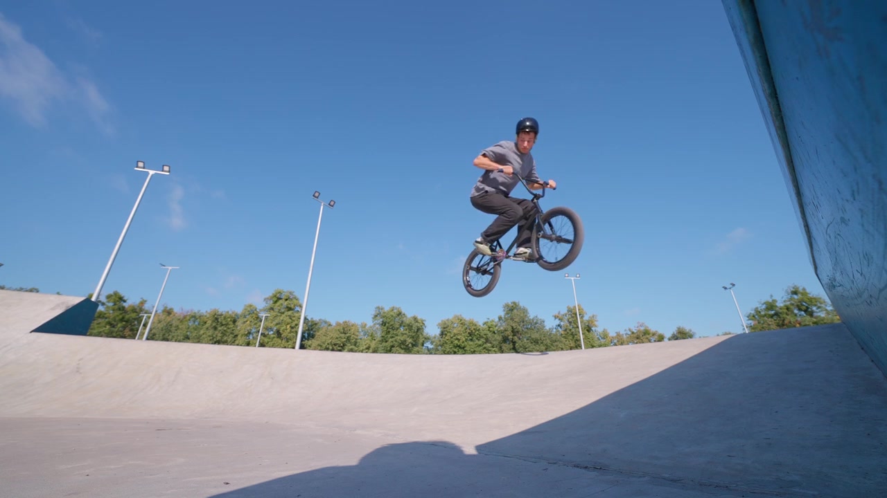 Giovane uomo in BMX che salta in alto in uno skatepark