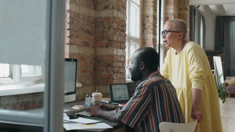 diverse colleagues discussing project on computer in office