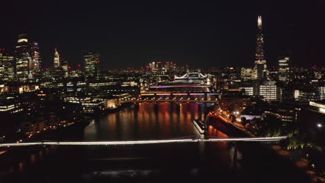 Forwards-fly-above-Thames-river.-Night-scene-of-city-centre.-Calm-water-surface-reflection-city-lights.--London,-UK