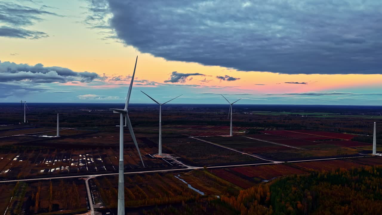 Aerial of wind farm and fields under a dramatic, cloudy sunset and twilight sky