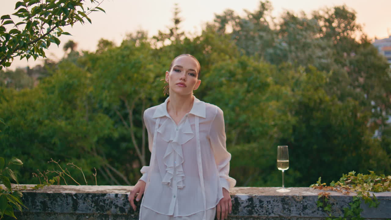 바에서 포즈를 취하는 패션 소녀와 와인 글래스 카메라. 발코니에 있는 여자