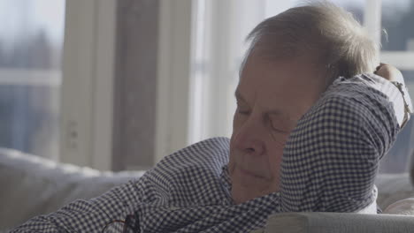 close face portrait of talking senretirement ior man in deep serious discussion on sofa at home