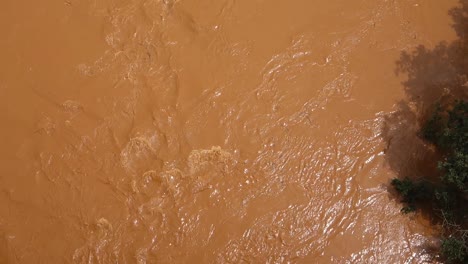 top view of strong current of muddy and turbulent river flowing down its course