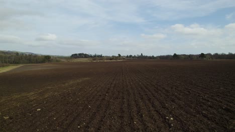 drone flying low over freshly ploughed fields in scotland