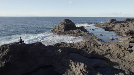 在加爾達海岸上空拍攝, 可以看到一個女人坐在大石頭上, 欣賞海浪和風景.