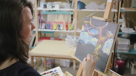 woman painting a tree in an art studio