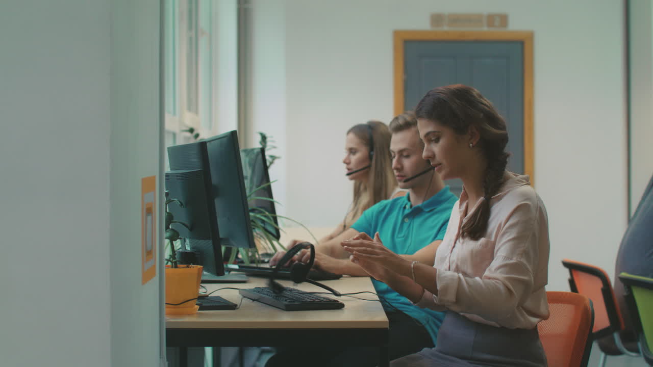 mujer joven hablando con clientes en el coworking. trabajador cansado lanzando auriculares.